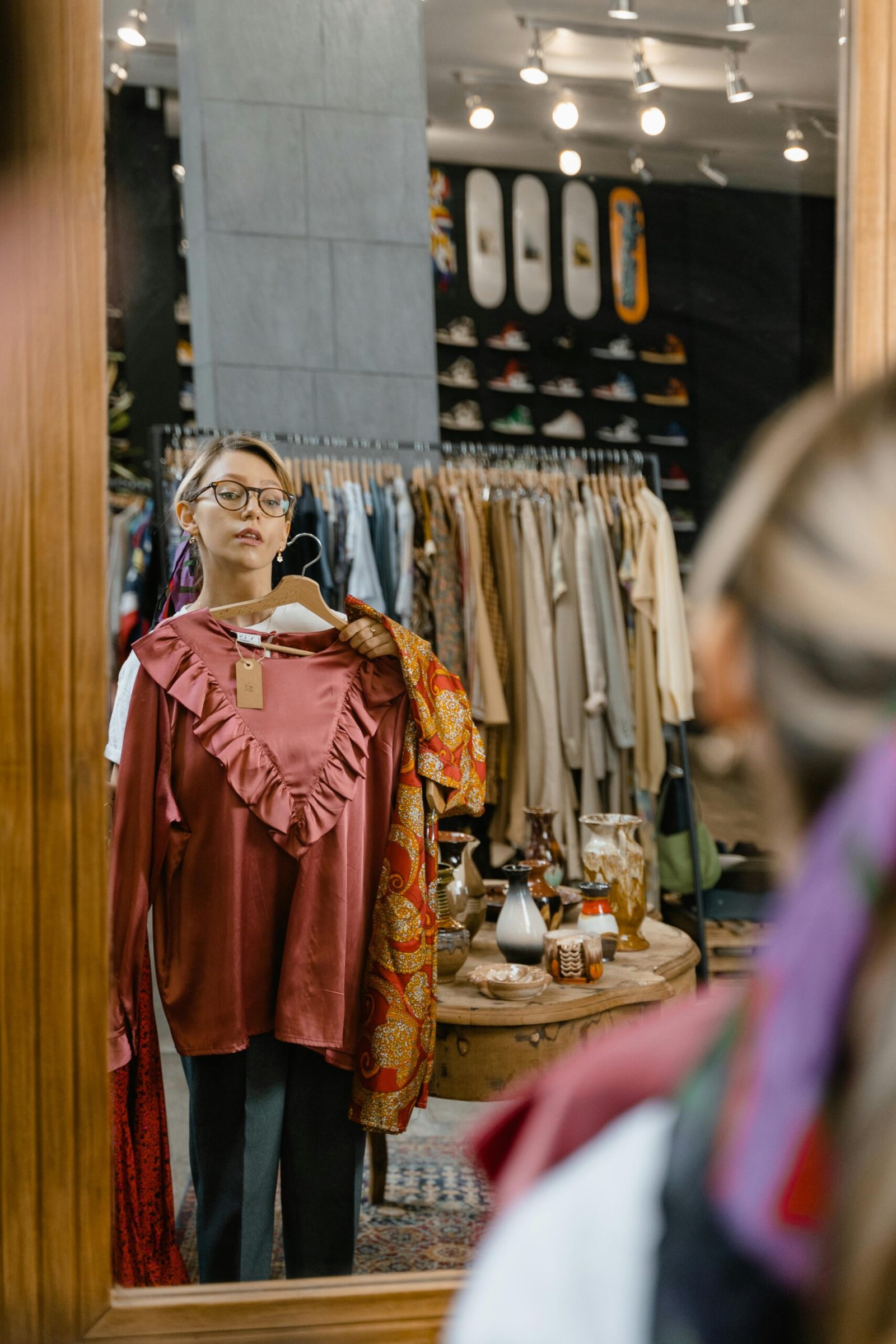 A woman tries on clothes in a stylish boutique, captured in a reflective mirror shot.